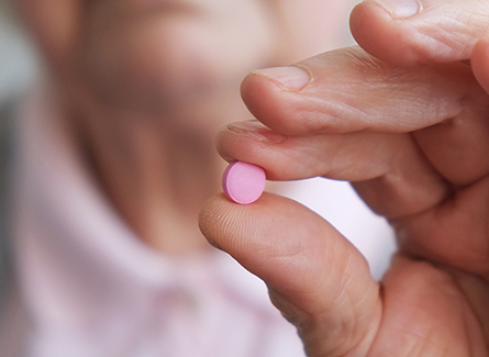 Woman holding baby aspirin between fingers