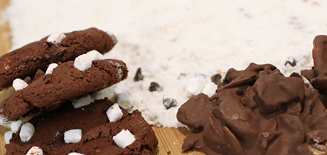 chocolate cookies topped with mini marshmallows sitting next to almond clusters