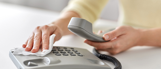 hand with a cloth wiping office phone