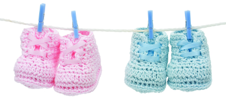 two pairs of knitted baby booties hung on a line with clothespins