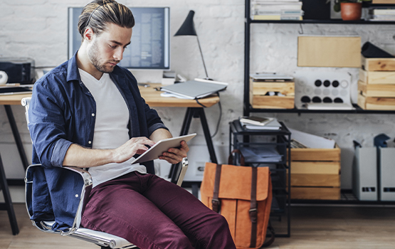 younger man sitting in chair looking at a tablet