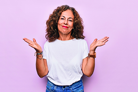 Woman shrugging on pink background