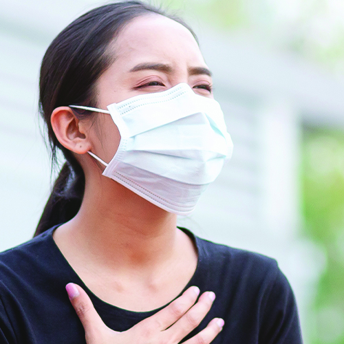 woman wearing face mask with hand on her chest