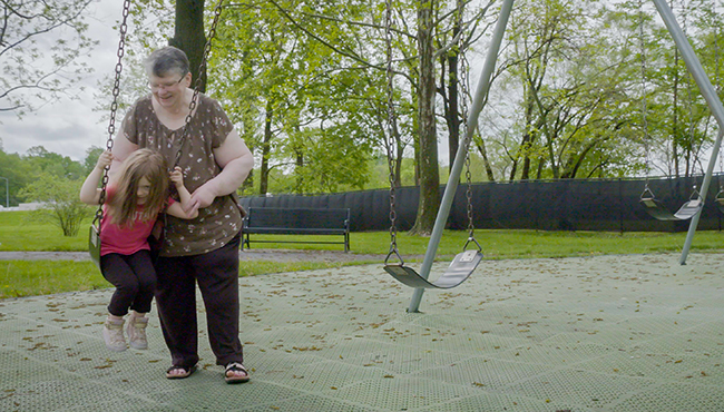 grandma at park with granddaughter swinging