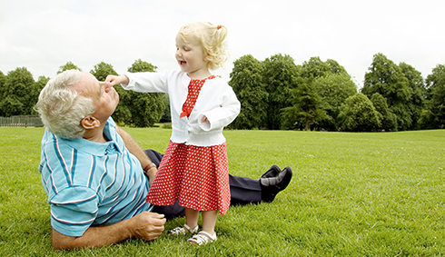 grandfather with toddler granddaughter lying on the grass