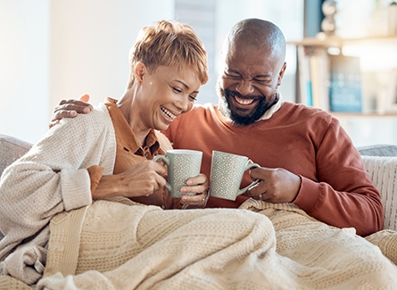 Older couple drinking coffee on couch, laughing